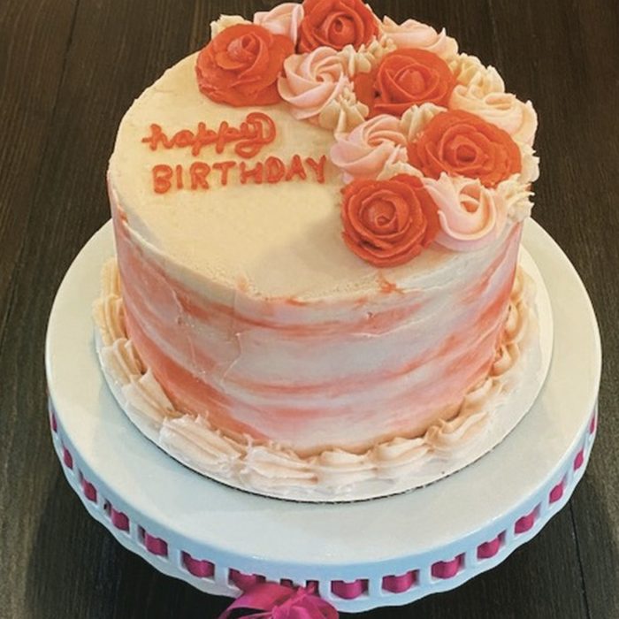 Round birthday cake with orange and pink buttercream roses
