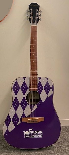 Purple argyle acoustic guitar with the SONGS Foundation 10th anniversary logo
